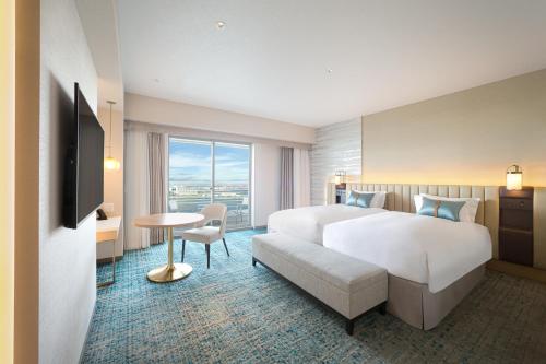 a hotel room with a large bed and a table at Kobe Meriken Park Oriental Hotel in Kobe