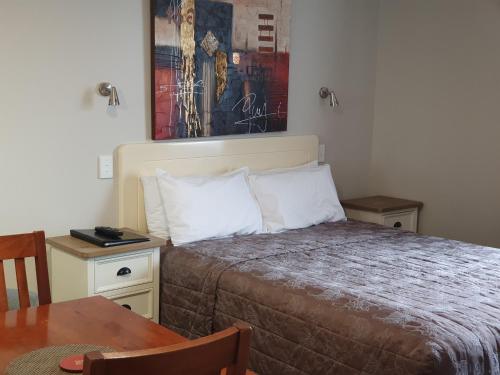 1 dormitorio con cama y mesa con sidx sidx sidx sidx en Panorama Motor Lodge, en Timaru