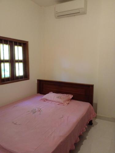 een slaapkamer met een bed met een roze deken bij San villa in Sulutanagoda
