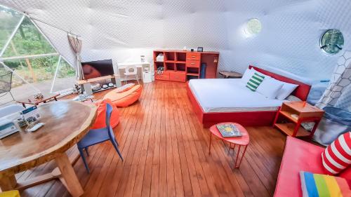 un soggiorno con letto e tavolo e una sala da pranzo di Bitzu Dome-Bijagua Riverside Glamping a Bijagua