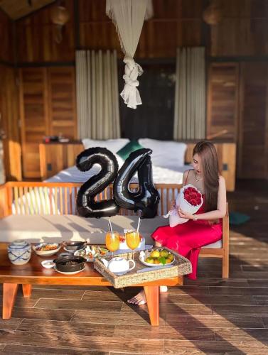 a woman sitting on a chair with a table with a cake at The Ruong Resort in Vung Tau