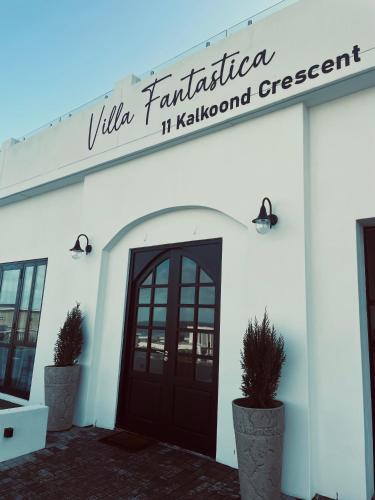 a white building with a door and a sign on it at Yzerfontein Villa Fantastica - No Loadshedding in Yzerfontein