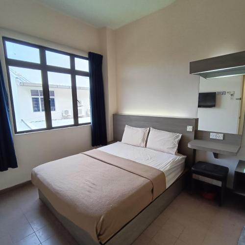 a bedroom with a bed with a window and a desk at Park City Motel in Malacca