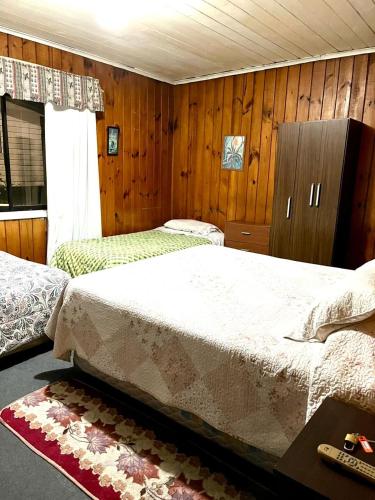 2 letti in una camera con pareti in legno di Hospedaje Centro Valdivia a Valdivia