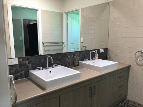 a bathroom with two sinks and a large mirror at House of the Young - Emu Bay in Emu Bay