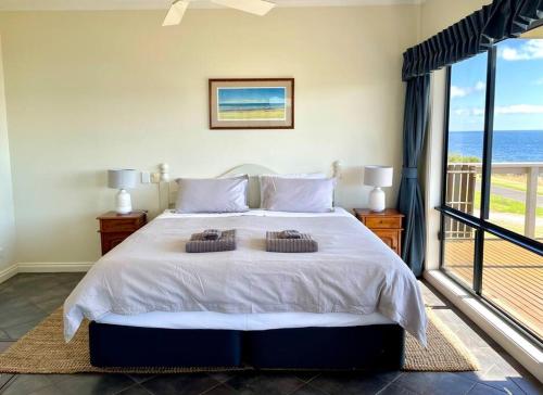 a bedroom with a bed with a view of the ocean at House of the Young - Emu Bay in Emu Bay