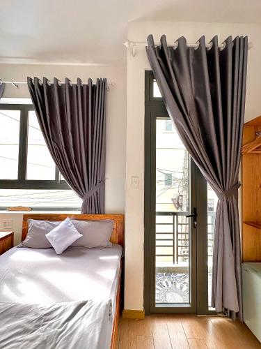 a bedroom with a bed and a window with curtains at Khoảng Lặng ATP in Da Lat