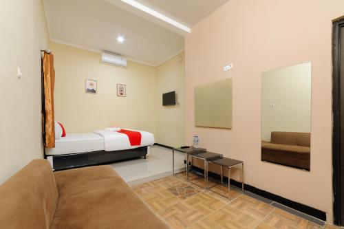 ボゴールにあるRedDoorz near The Jungle Waterpark Bogorのベッド1台、ソファ、鏡が備わる客室です。