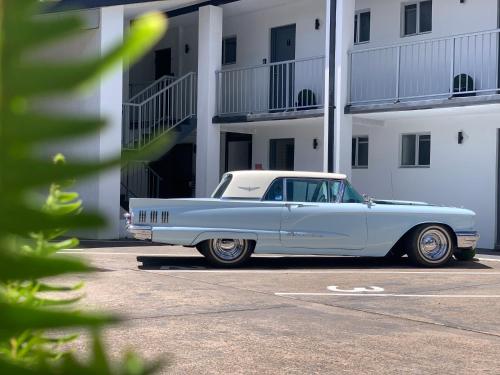 a white car parked in a parking lot next to a building at Zorba Waterfront Motel in Batemans Bay
