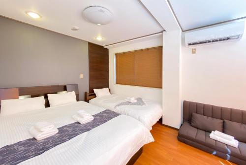 a bedroom with two beds and a couch at Uhome Mitomi Home 3F in Tokyo