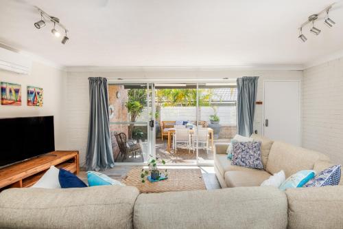 a living room with a couch and a tv at Sawtell Beachfront Villa - 2 mins to everything! in Sawtell