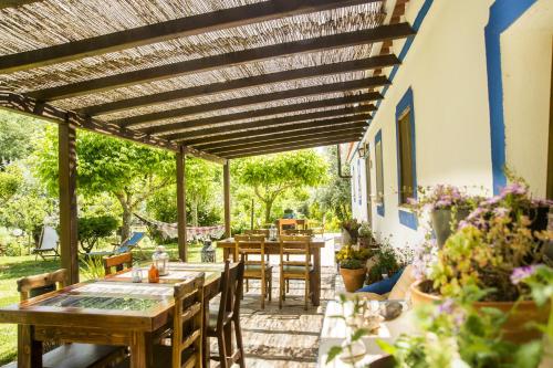 a patio with tables and chairs under a wooden pergola at Figueirinha Ecoturismo in Montes da Estrada