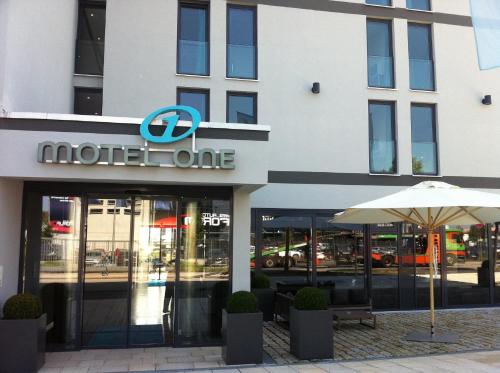 a hotel one with an umbrella in front of a building at Motel One München-Garching in Garching bei München