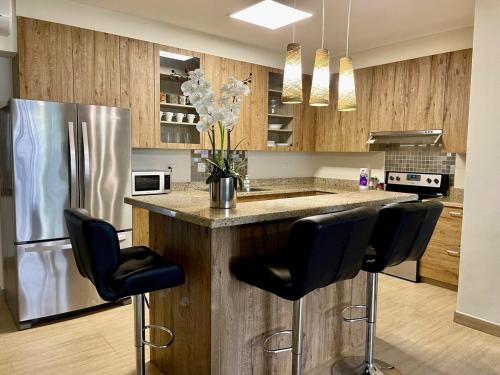 a kitchen with a counter with chairs and a refrigerator at Tumon Isa 16 Condo in Tamuning