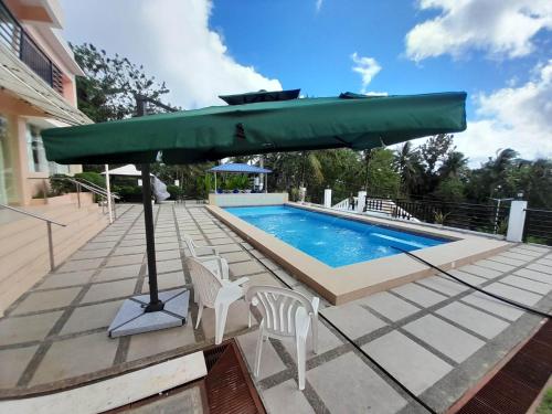 a large green umbrella sitting next to a swimming pool at MaisonDeGloria in Legazpi