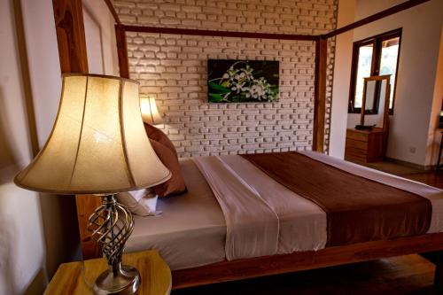 a bedroom with a bed with a lamp on a table at Benjamin Cottage Haputale in Haputale