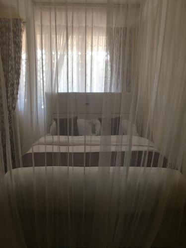 ein Bett mit weißen Vorhängen in einem Schlafzimmer in der Unterkunft Mountainview house#122 in Kisumu