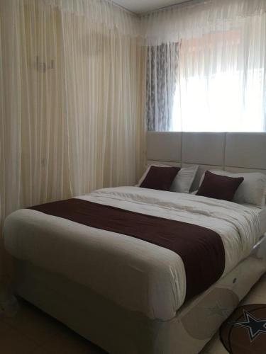 duże łóżko w sypialni z oknem w obiekcie Mountainview house#122 w mieście Kisumu