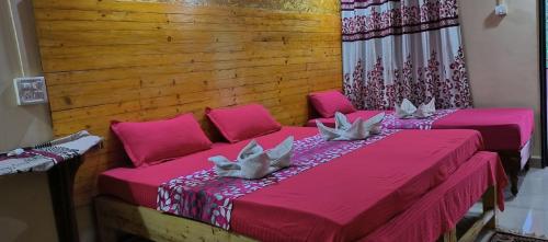 2 łóżka w pokoju z różową pościelą i poduszkami w obiekcie ALEGRO HOLIDAY HOMES w mieście Palolem