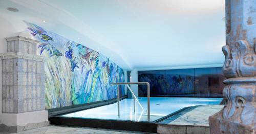 a swimming pool with a mural on the wall at Dorfhotel Beludei in Santa Cristina in Val Gardena