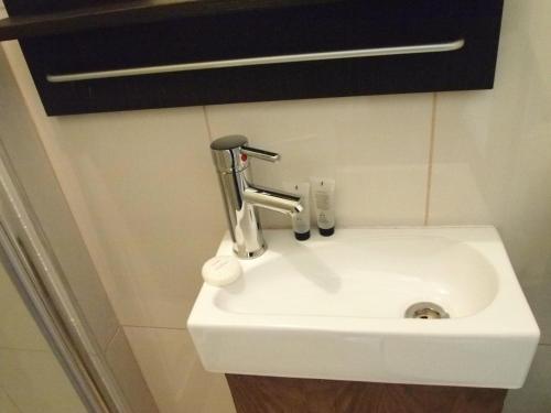 a white sink with a faucet on a wall at Earls Court Garden Hotel in London