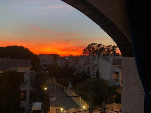 Una vista de una puesta de sol desde un arco de una ciudad. en Apartamento, 3° línea de playa, en Cubelles