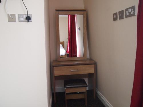 a mirror on a dresser in a room at Earls Court Garden Hotel in London
