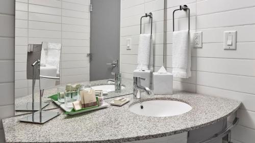 La salle de bains est pourvue d'un lavabo et de deux miroirs. dans l'établissement Matrix Hotel, à Edmonton
