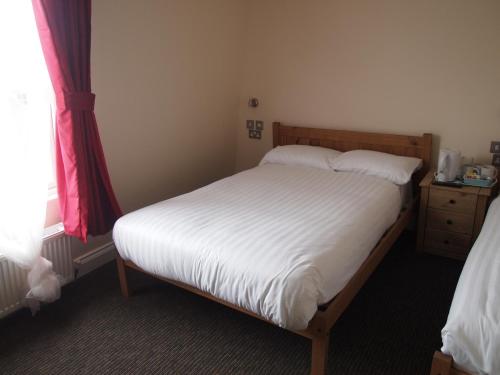 a bedroom with a bed with white sheets and a window at Earls Court Garden Hotel in London