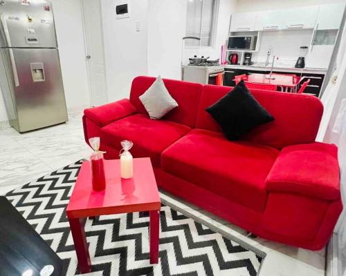 a red couch in a living room with a table at Departamento La Punta E - Piscina - Zona parrilla in Lima