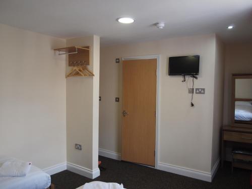 a room with a bed and a door with a television at Earls Court Garden Hotel in London