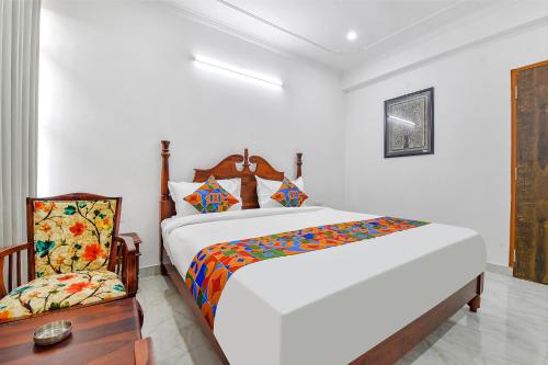 a white bedroom with a large bed and a chair at FabHotel Umrao Haveli in Jaipur