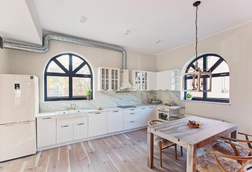 a kitchen with white cabinets and a wooden table at Apartamenty Strażacka - Loft SoHo in Szczecinek