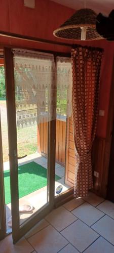- une porte en verre ouverte avec des rideaux dans la chambre dans l'établissement chalet du cypres, à Cornimont