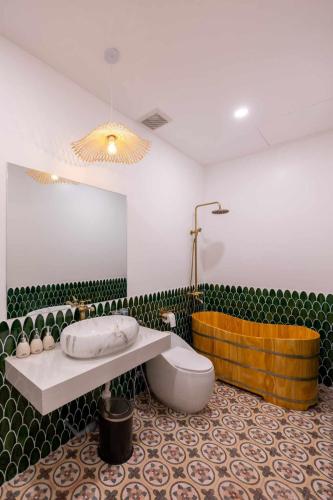 a bathroom with a tub and a toilet and a sink at Pisces Hotel Hue in Hue