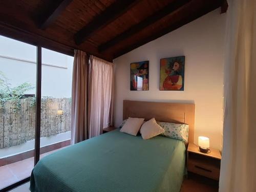 1 dormitorio con cama verde y ventana grande en At Home Realejo, en Granada