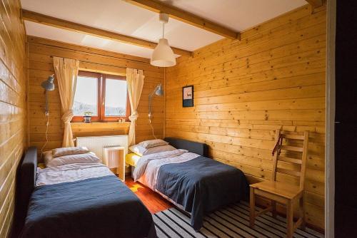 two beds in a room with wooden walls at Osada Bura Polana in Ujsoły