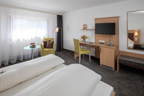 a hotel room with a bed and a desk at Landhotel Sonnenhalde in Bad Boll