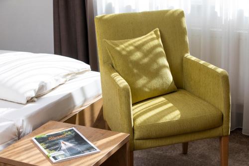 a green chair sitting next to a bed and a table at Landhotel Sonnenhalde in Bad Boll