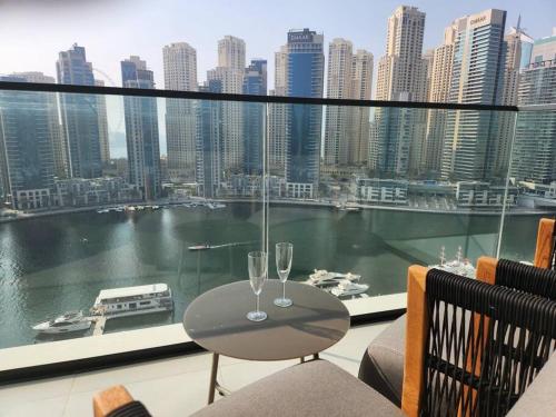 ドバイにあるVida Dubai Marina & Yacht Club, 1 BR with Marina and Sea Viewのバルコニーの上にテーブルとワイングラス2杯