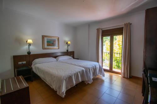 a bedroom with a bed and a large window at Hotel del Carmen in Prado del Rey