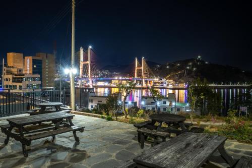 a group of picnic tables with a bridge in the background at Yeosu View Foret Pension in Yeosu