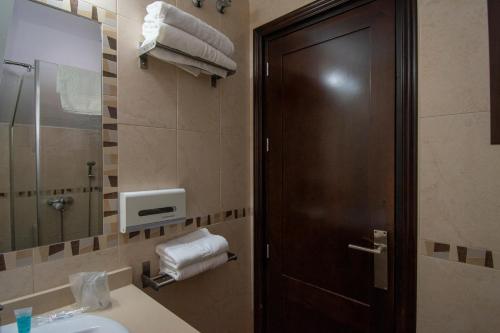 ein Badezimmer mit einem Waschbecken und einer Holztür in der Unterkunft Hotel del Carmen in Prado del Rey