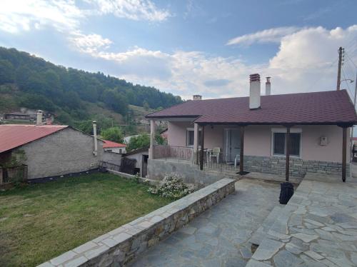 a house with a stone retaining wall and a yard at Primoula Grammou 1450 in Néa Kotýli