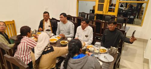 a group of people sitting around a table eating food at Gulsitara Resorts-Gulmarg in Gulmarg