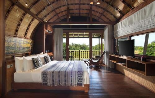 a bedroom with a bed and a television in it at Beehouse Dijiwa Ubud in Ubud