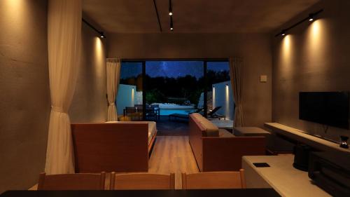 a living room with a couch and a television at フェリスヴィラスイート伊良部島・長浜ベイ in Miyako Island