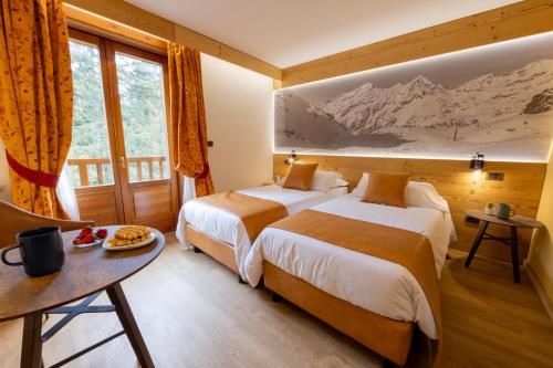 um quarto de hotel com duas camas e uma mesa em Hotel Petit Tournalin em Champoluc