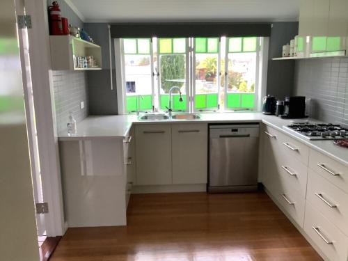 a kitchen with white cabinets and a sink and a window at Rosellas on Corundum Cottage - treat yourself! in Stanthorpe