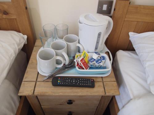 a table with a coffee maker and cups on a bed at Earls Court Garden Hotel in London